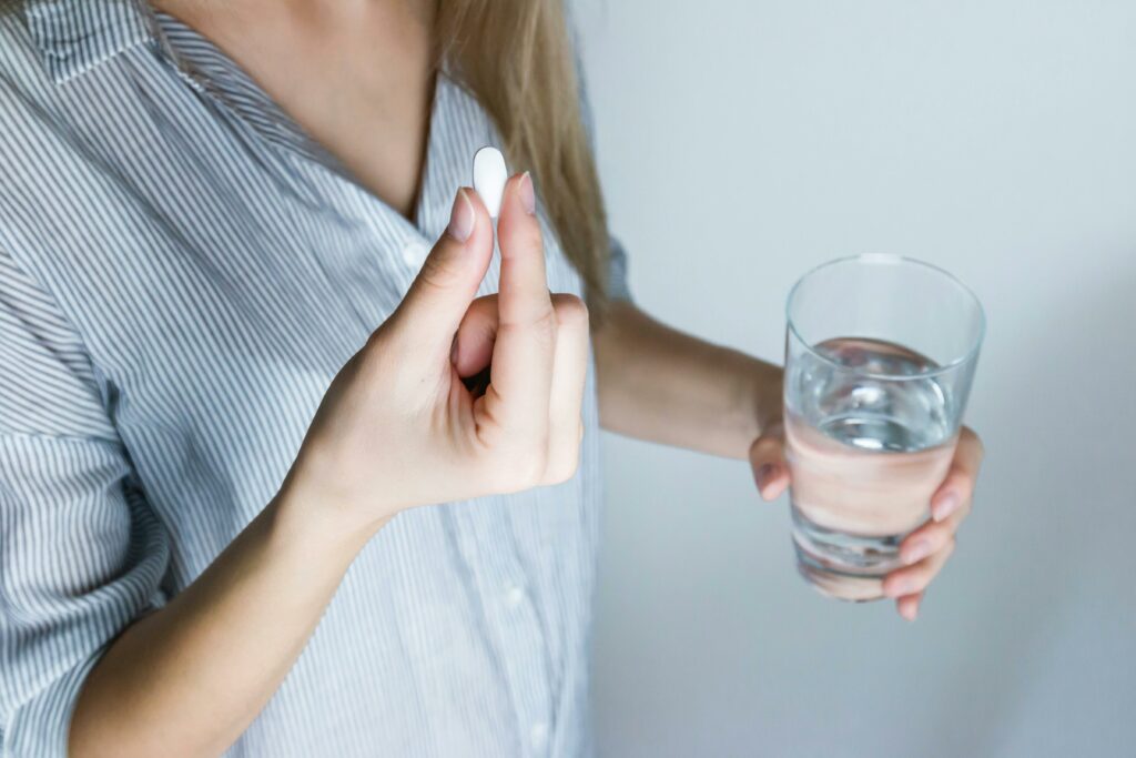 pexels photo 576831 576831 Close-up of a woman holding a pill and a glass of water, ready to take medication.